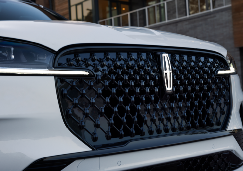 The black grille of a white 2025 Lincoln Aviator® SUV is shown with its fog lights on. | Bozard Lincoln in Saint Augustine FL