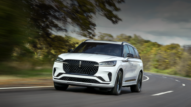 A white 2025 Lincoln Aviator® SUV is being driven down a road lined with trees. | Bozard Lincoln in Saint Augustine FL