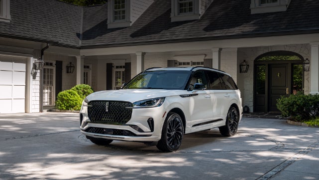 A white 2026 Lincoln Aviator® SUV is parked in the driveway of a luxury home. | Bozard Lincoln in Saint Augustine FL