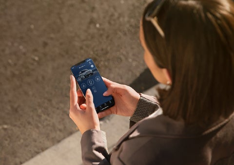 A person is shown interacting with a smartphone to connect to a Lincoln vehicle via the Lincoln Way® app. | Bozard Lincoln in Saint Augustine FL
