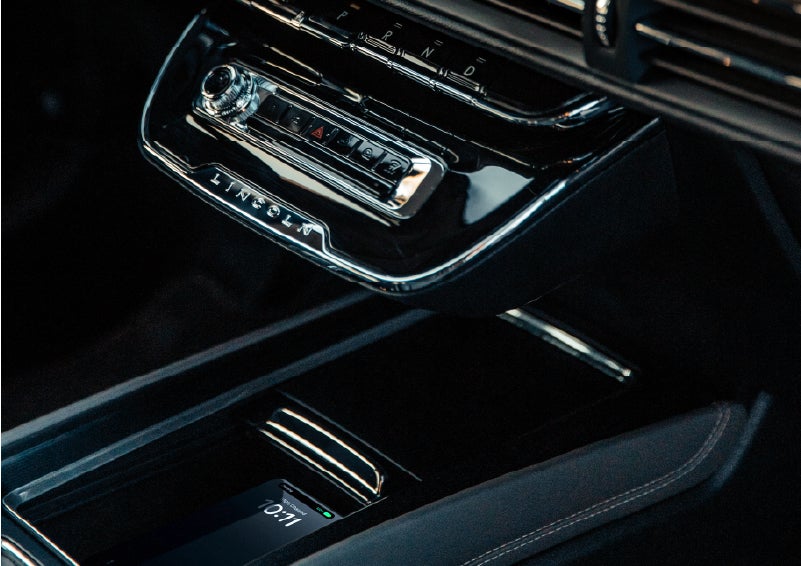 A smartphone rests on the available wireless charging pad in the front center console cubby. | Bozard Lincoln in Saint Augustine FL