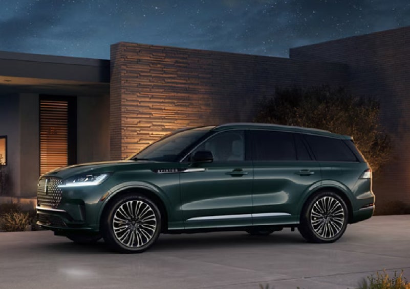 A green 2027 Lincoln Aviator® SUV is parked outside a contemporary home. | Bozard Lincoln in Saint Augustine FL