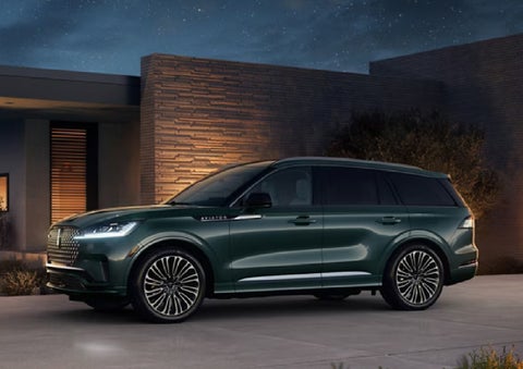 A green 2027 Lincoln Aviator® SUV is parked outside a contemporary home. | Bozard Lincoln in Saint Augustine FL