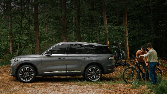 A father and son load e-bikes on a bike rack attached to a 2027 Lincoln Aviator® SUV. | Bozard Lincoln in Saint Augustine FL