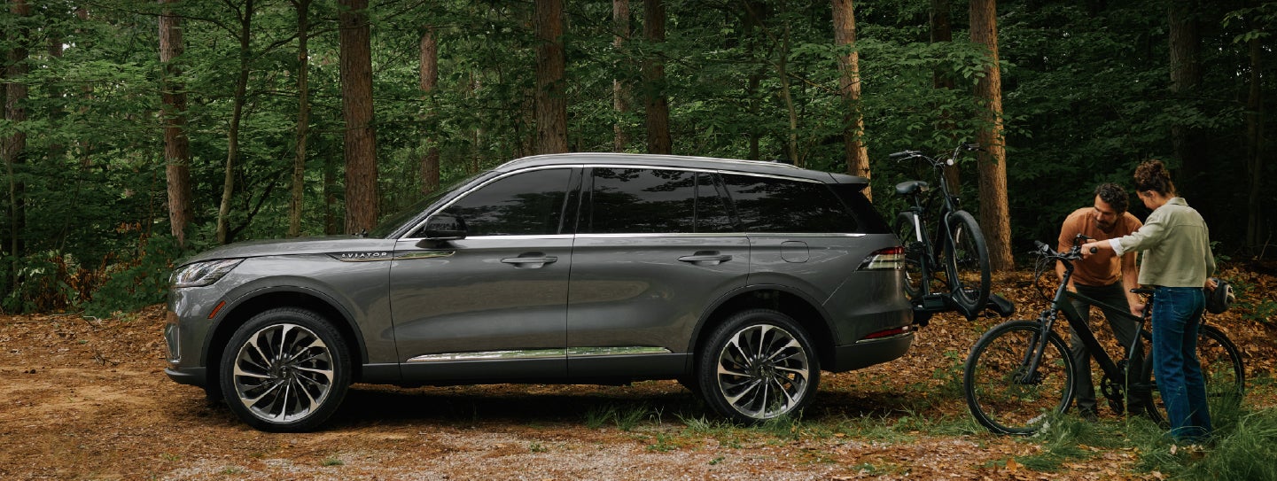 A father and son load e-bikes on a bike rack attached to a 2027 Lincoln Aviator® SUV. | Bozard Lincoln in Saint Augustine FL